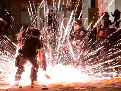 TOPSHOT - A firecracker thrown by protesters explodes under police one block from the Whit