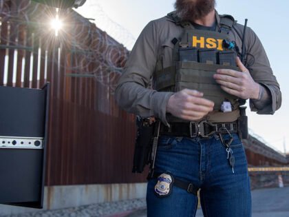 An HSI agent gears up for a mission next to the US/Mexico border wall in Nogales, AZ.