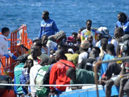 First responders and members of the Red Cross tend to migrants disembarking from a boat at