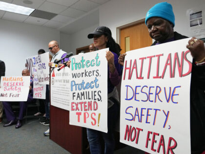 People hold signs during a rally in support of the extension of Temporary Protected Status