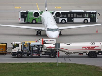 14 April 2026, Bavaria, Munich: A refueling vehicle (front) drives past a passenger aircra