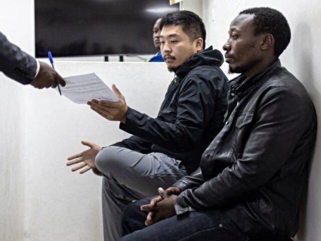 Chinese national, Zhan Kequn (L) receives a copy of the charge sheet from his counsel as h