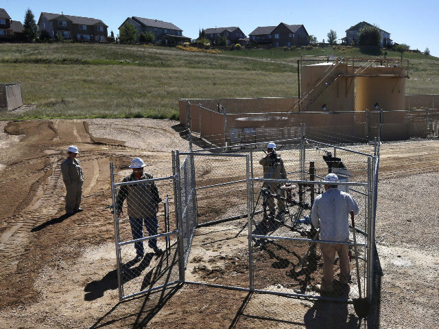 In this Sept. 25, 2013 file photo, employees work at a natural gas extraction well head in