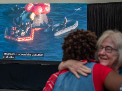 People hug as they watch a live broadcast of the return of the Artemis II crew members to