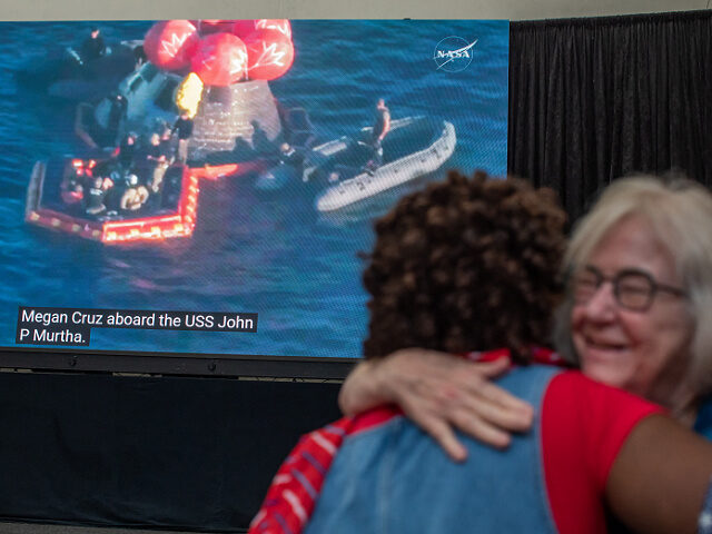 People hug as they watch a live broadcast of the return of the Artemis II crew members to