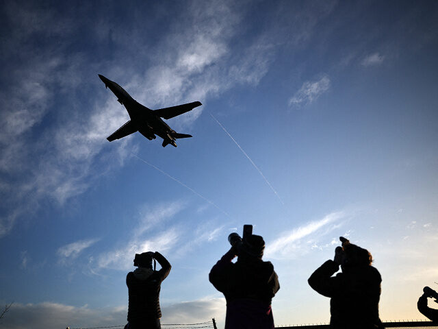 People take photographs as a US Air Force (USAF) B-1 Lancer bomber jet takes off from RAF