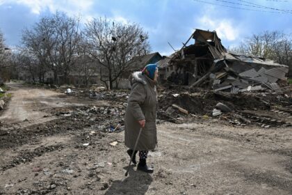 A local resident walks past a destroyed house following an air attack in Yasynuvata, Russi