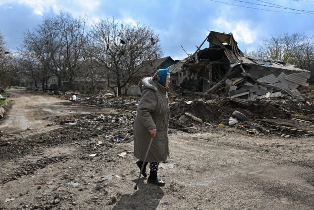 A local resident walks past a destroyed house following an air attack in Yasynuvata, Russi
