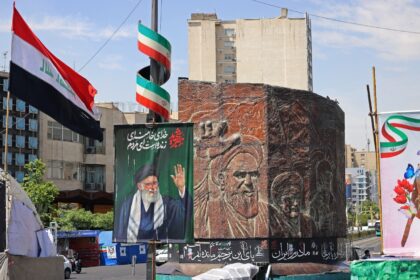Commuters make their way past a picture of Iran's slain supreme leader Ayatollah Ali
