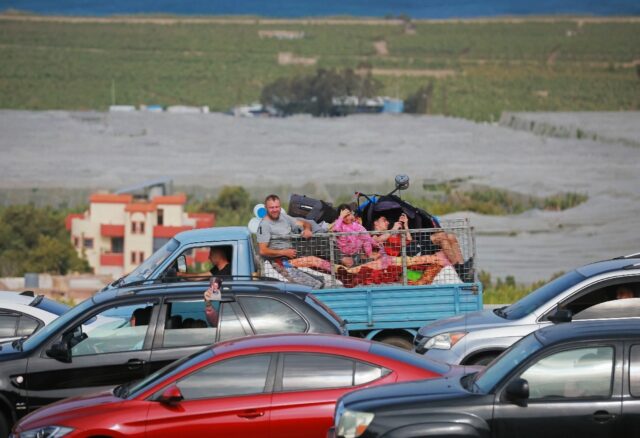 Displaced residents travel back to their homes via the bombed Qasmiyeh bridge over the Lit