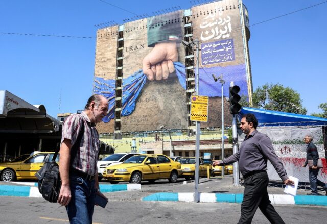 Iranians walk past a billboard referring to the Strait of Hormuz in Tehran's Vanak Sq