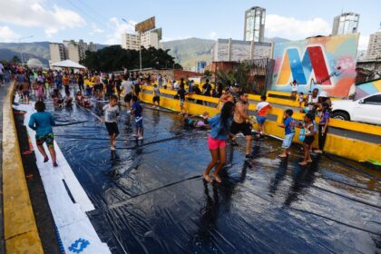 People slide on wet plastic during Carnival celebrations in Caracas on February 16, 2026