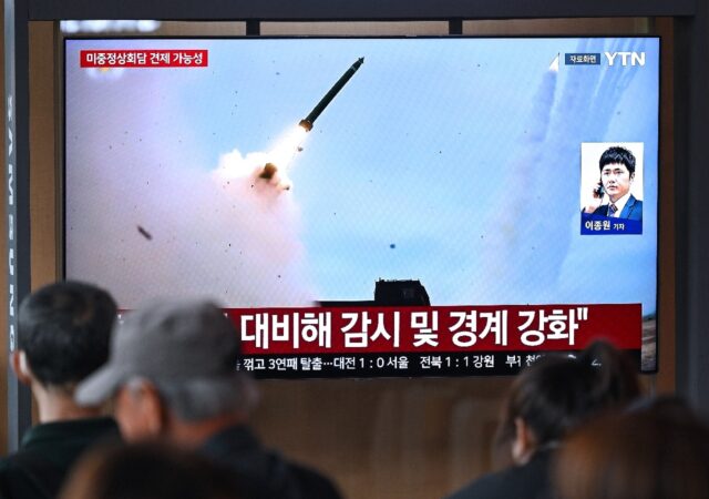 People watch a news broadcast with file footage of a North Korean missile test at a Seoul
