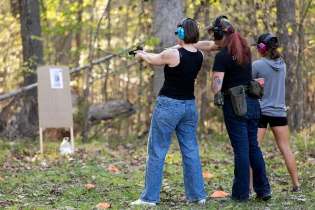 A student (L) prepares to shoot as Clara Elliott (C) instructs proper technique during an