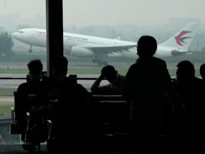 FILE - Passengers wait for their flight as a China Eastern flight takes off from the runwa
