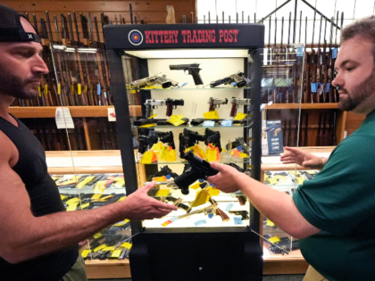 Aaron Fondry, left, is handed a 9mm pistol by Bryan Hodge, asst. manager of firearms, whil