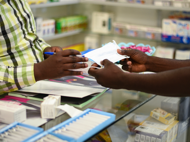FILE — In this Feb. 6, 2020 file photo, a man buys a face mask at a pharmacy in Kitwe, Z
