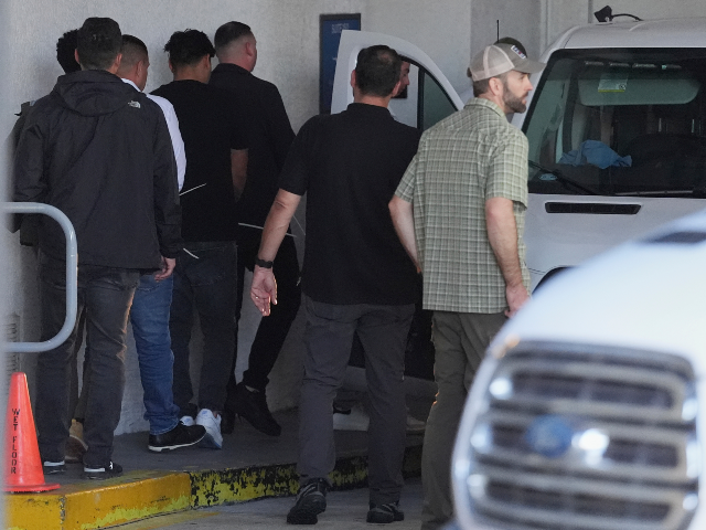 Plainclothes agents from U.S. Immigration and Customs Enforcement load people detained at