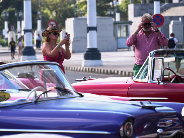 Tourists take photos of classic American cars in Havana, Monday, Jan. 26, 2026. (AP Photo/