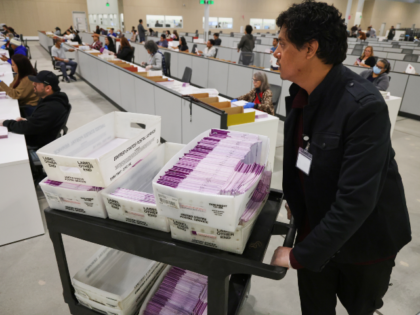 FILE - A worker pushes a cart of received mail ballots at the L.A. County Ballot Processin