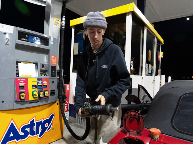 Luciano V. replaces the fuel nozzel after filling the tank of their 1999 Mazda Miata at an