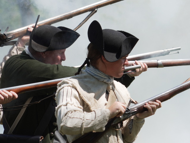 AP26133678828868 Smoke envelopes a group of re-enactors following a musket volley during a Revolutionary Wa