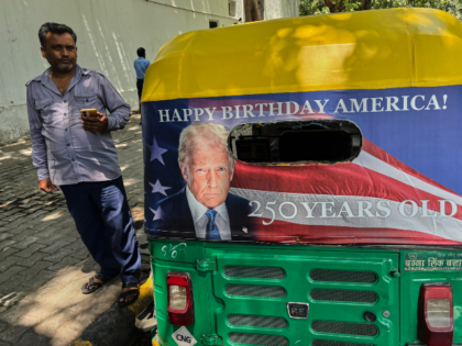 Pradeep Kumar stands next to his auto-rickshaw featuring a poster of U.S. President Donald