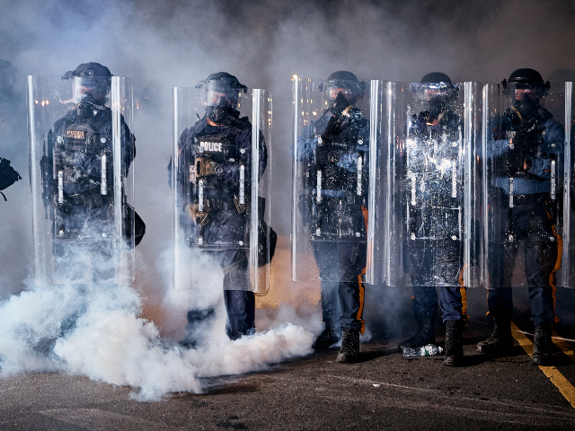 State police officers stand behind shields as tear gas fills the area outside the Delaney