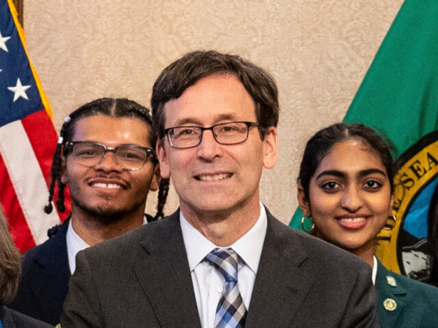 Washington Gov. Bob Ferguson, center, stands during a signing ceremony for a bill relating