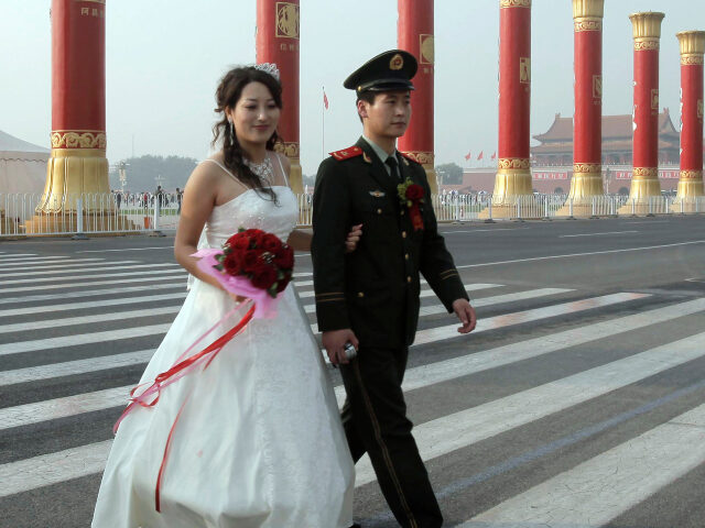 A Chinese paramilitary officer and his bride walk on the zebra crossing during a mass wedd