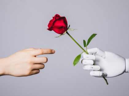 human hand reaching for red rose in robotic hand (Kilito Chan/Getty Images)
