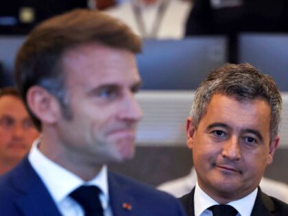 France's President Emmanuel Macron (C) reacts next to France's outgoing Minister for Inter