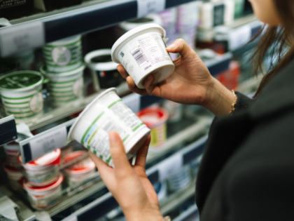 A detailed view of a consumer's hands holding two food containers to compare ingredie