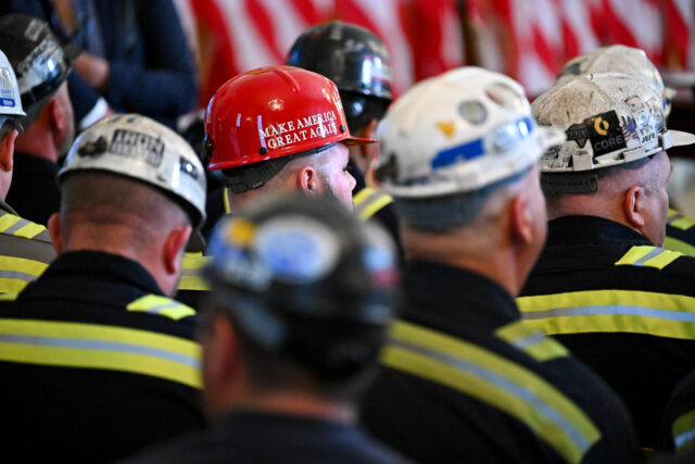 A worker wears a "Make America Great Again" sticker on a hard hat while attendin