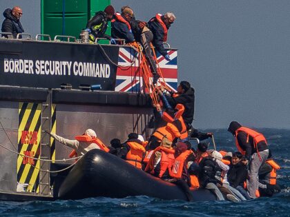 AT SEA, ENGLAND - APRIL 27: Migrants on an inflatable 'small boat' clamber on to The UK Bo