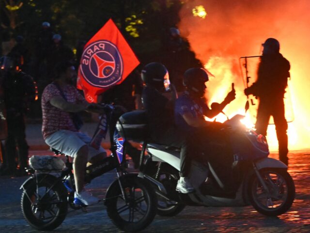 PSG supporters drive their scooters past anti-riot police officers (Rear R) as they celebr