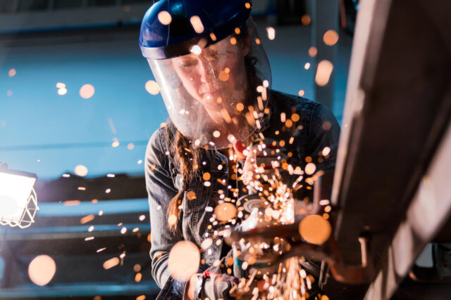 Female welder working in her workshop using an angle grinder. Los Angeles, America. Octobe