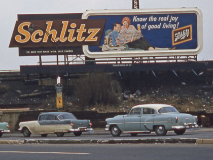 1st October 1960: New York City - Cars on Woodhaven Boulevard drive past a Schlitz beer bi