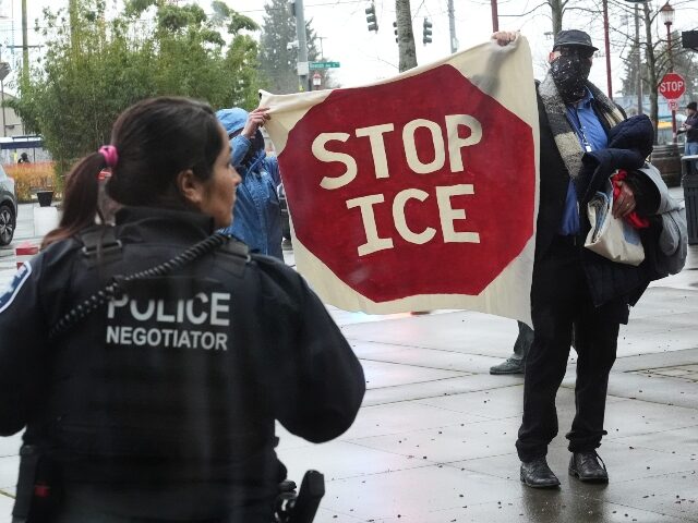 Protesters hold up a "Stop ICE" sign after being removed from the building by Se