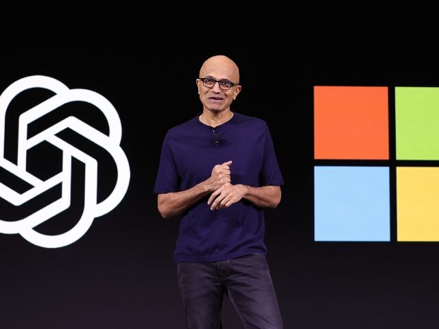 Satya Nadella between logos for Microsoft and OpenAI