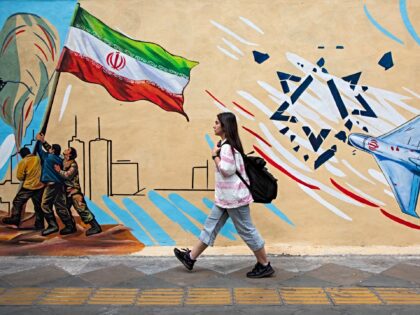 TEHRAN, IRAN - APRIL 12: A woman passes in front of a pro-government political mural on Ap