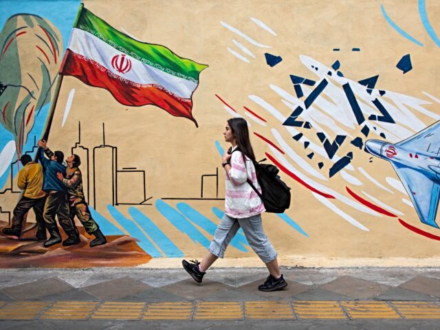 iran talks TEHRAN, IRAN - APRIL 12: A woman passes in front of a pro-government political mural on Ap