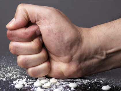 man's fist crushing pills
