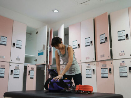 young woman organizing workout gear in a gym locker room,