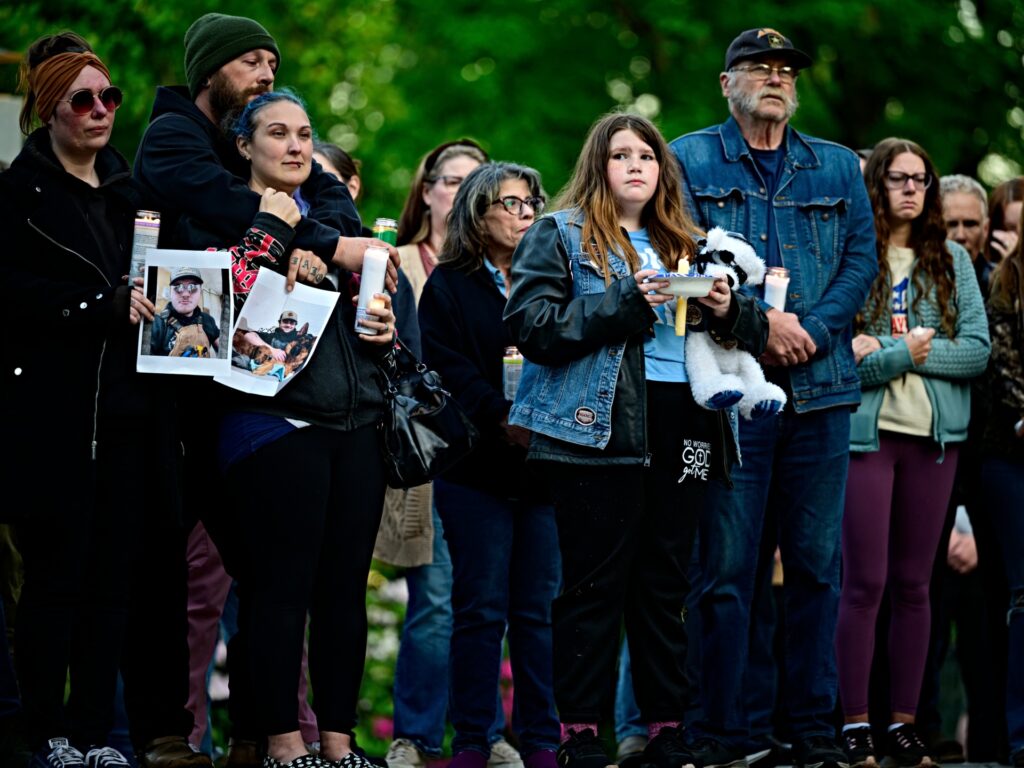 LONGVIEW, WASHINGTON - MAY 26: Community members hold photographs of loved ones during a vigil at R.A. Long Park following a fatal chemical storage tank failure on May 26, 2026 in Longview, Washington. One person was killed, while 10 others were injured, and nine employees remain unaccounted for following a catastrophic storage tank failure involving corrosive "white liquor" at the paper mill Tuesday morning. (Photo by Mathieu Lewis-Rolland/Getty Images)