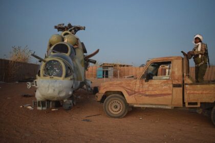 An Azawad Liberation Front fighter next to a damaged Mi-24 helicopter at the former Russia