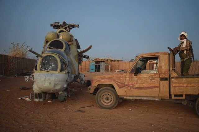An Azawad Liberation Front fighter next to a damaged Mi-24 helicopter at the former Russia
