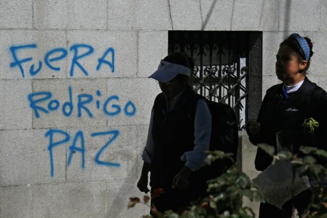 Bolivian women walk past graffiti reading 'Rodrigo Paz out,' referring to the country's new center-right president Bolivian women walk past graffiti reading 'Rodrigo Paz out,' referring to the co