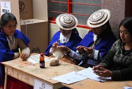 Indigenous Misak women serving as election officials knit as they wait for voters at a pol