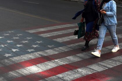 Iranians walk across a street painted with a US flag in Tehran, where citizens are dubious